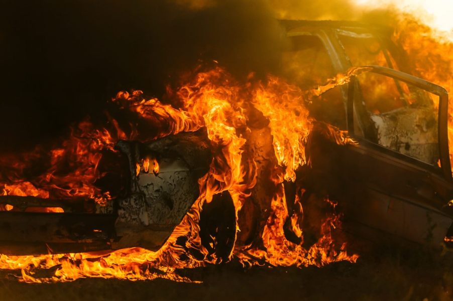 A car on fire with smoke and flame.