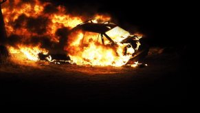 A car fire sends flames and smoke into the air.