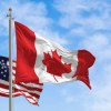 An American and a Canadian flag fly above a car park.