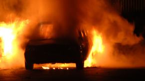 A firefighter approaches a raging car fire.