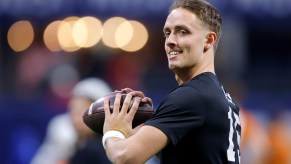 Quarterback Carson Beck throwing a football, the stadium in the background