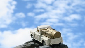 Toy pickup truck with coins in its bed in front of a blue sky