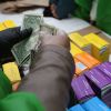 A person counting money near Girl Scout cookies