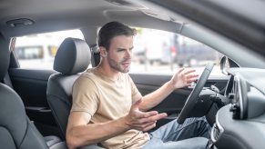 Angry driver gestures at Jeep warranty spam on his infotainment screen.