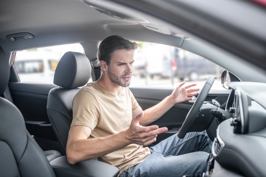 Angry driver gestures at Jeep warranty spam on his infotainment screen.