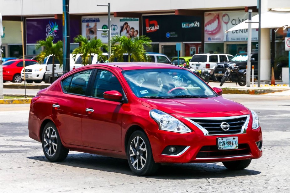 Red Nissan Versa driving through Cancun, Mexico.