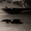 Black oil leaking from the bottom of a car onto concrete