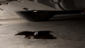 Black oil leaking from the bottom of a car onto concrete