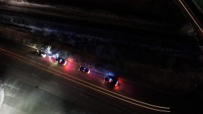 Police cars stop a vehicle on a highway in the dark.