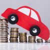 Red toy car driving down a pile of coins.