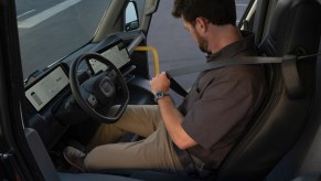 Man buckles into the driver seat of the Rivian electric delivery fleet van.