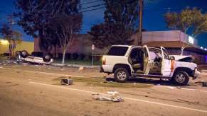 Whet SUV at a crash scene, a flipped sedan visible in the background.