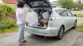 Woman pulls a bag of trash out of a stolen car returned full of junk