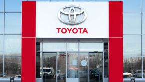 The Toyota logo above the door of a dealership selling hybrid EVs and traditional cars