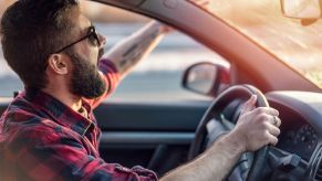 An angry driver yelling and waving their arm out of the window