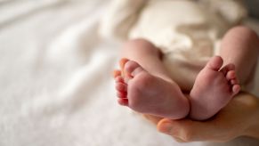 A newborn baby's feet, cradled by the mother's hands