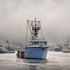 A blue fishing boat navigating a harbor