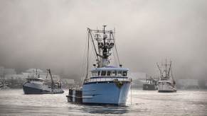 A blue fishing boat navigating a harbor