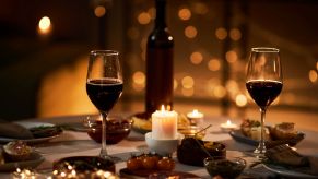 Two glasses of wine on a candlelit table to emulate a date night