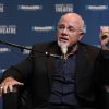 Dave Ramsey sits on an event stage speaking into a mic