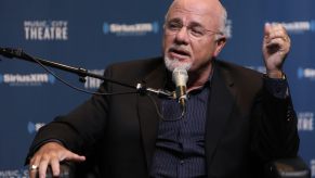 Dave Ramsey sits on an event stage speaking into a mic