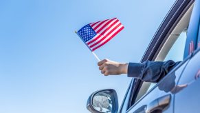 Driver holding a small American flag out of the left front window in close view