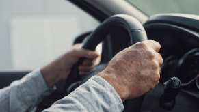 Elderly person's hands on steering wheel driving