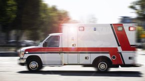 An EMS ambulance driving in full left profile view