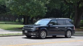 A black Ford Flex driving down a scenic route