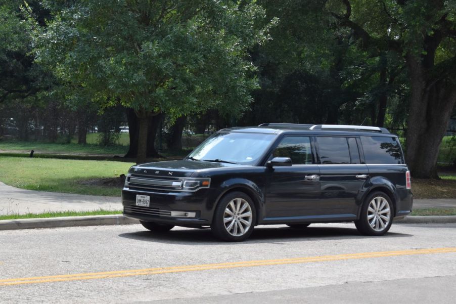 A black Ford Flex driving down a scenic route