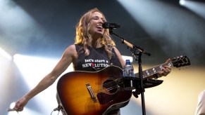 Sheryl Crow on stage singing and holding her guitar