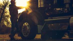 Truck driver stands next to his rig at dusk