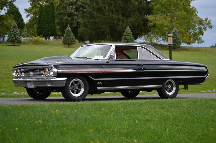 A black and pinstriped 1964 Ford Galaxie, one of the American cars influenced by the Space Race, parked in left angle profile view