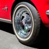 Closeup of the chrome wheels of a classic red, collectible Mustang