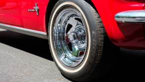 Closeup of the chrome wheels of a classic red, collectible Mustang