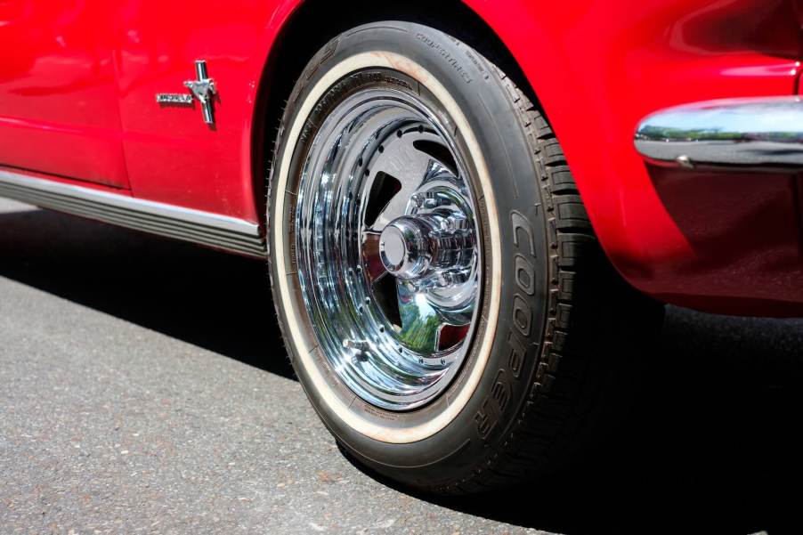 Closeup of the chrome wheels of a classic red, collectible Mustang