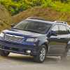 A dark blue 2012 Subaru Tribeca SUV driving on a dusty road