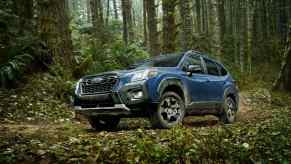 A blue 2022 Subaru Forester parked in a lush forest in left front angle view