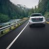 A 2024 GMC Sierra pickup truck driving on a tree-covered mountainous road