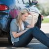 Sad driver sits by car totaled by insurance after minor fender bender accident.