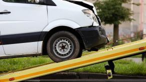 White van being loaded on a rollback with a smashed front after a florida man stole and crashed it.