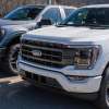 Two Ford F-150 pickup trucks parked at a new car dealership.