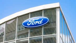 Huge Ford blue oval logo on the windows of a used car dealership.