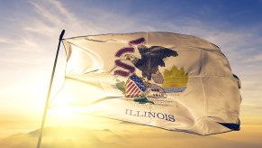 White Illinois state flag with the sun setting behind it.