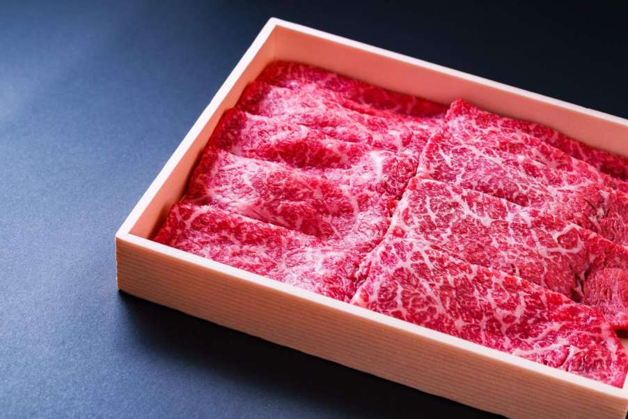 Wooden box of raw beef steaks.