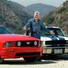 Collector Jay Leno stands between a pre-smog and post-smog Ford Mustang, mountains in the background