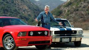 Collector Jay Leno stands between a pre-smog and post-smog Ford Mustang, mountains in the background