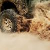 Tire of a Jeep Wrangler SUV kicking up a dust cloud running on steam power.