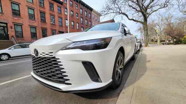 White Lexus RX 350 crossover SUV parked in front of a city street.