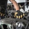 The hands of a Toyota Tundra mechanic trying to fix a seized motor.